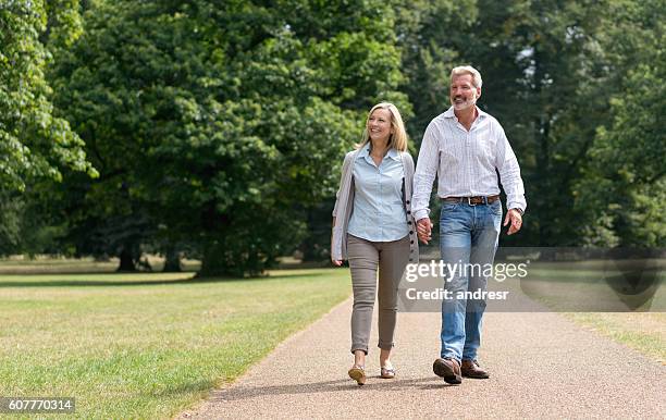 retired couple walking at the park - couple walking in park stock pictures, royalty-free photos & images