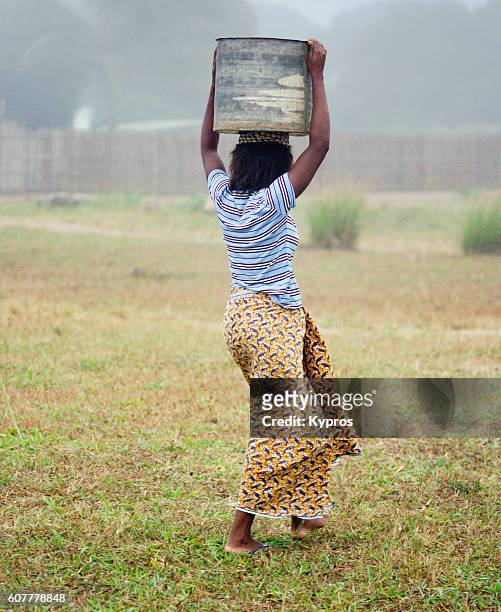 africa, southern africa, mozambique, mueda, view of woman walking carrying bucket on head. police charge about a penny per container for water (just because they have that power). the alternative is to walk to the river a kilometer or two away). (year 200 - south africa foto e immagini stock