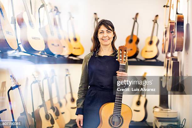 confident female worker holding guitar - guitar shop stock pictures, royalty-free photos & images