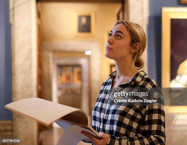 female art student at gallery, looking at painting - museo fotografías e imágenes de stock