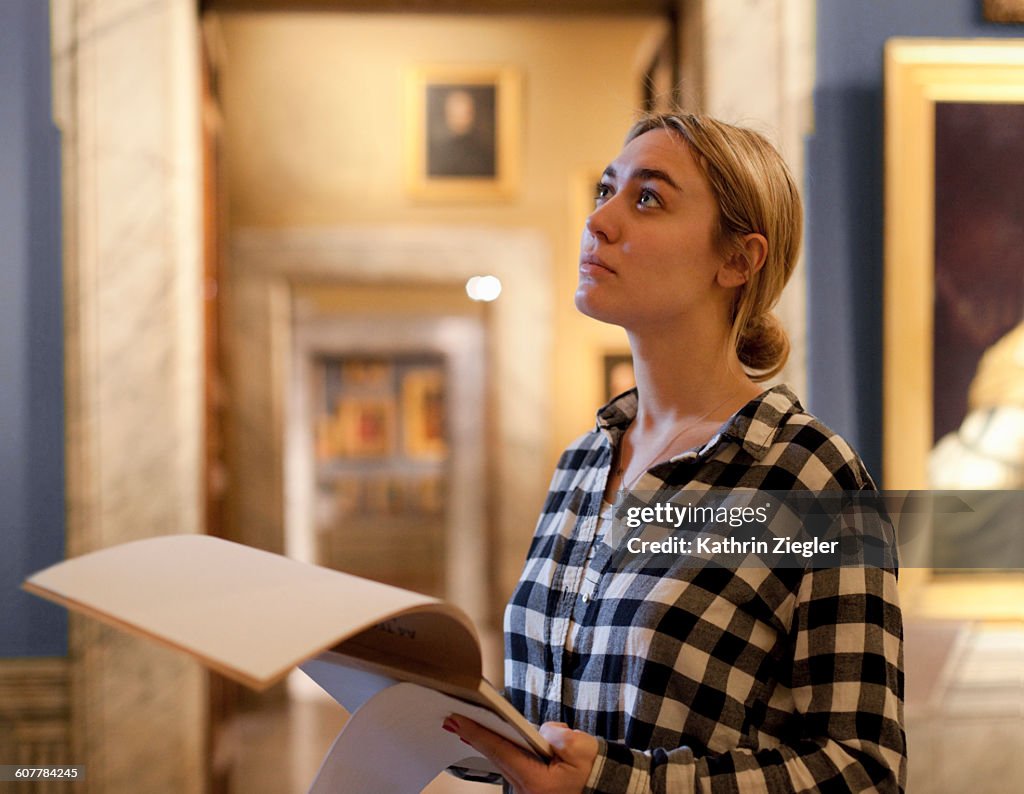 Female art student at gallery, looking at painting