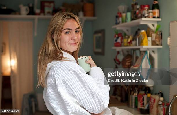 young woman in a bathrobe enjoying cup of coffee - bathrobe stockfoto's en -beelden