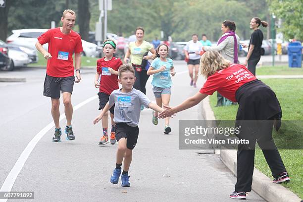 Luke DeBoni, 7 yrs old who's running for Janine and his Papa get high five near the finish line from Treva Thompson, organizer and cancer survivor at...