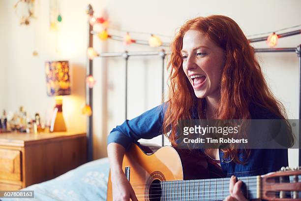 young woman singing with guitar - singing imagens e fotografias de stock