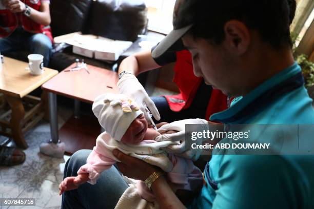 Health worker administers vaccine to a child during a vaccination campaign carried out by the Syrian Arab Red Crescent, on September 19 in the...
