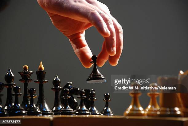 hand moving the pieces of a chess board, close-up - chess game stock-fotos und bilder