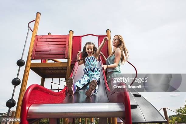 unten blick auf spielerische mutter und tochter auf einem spielplatz. - rutsche stock-fotos und bilder