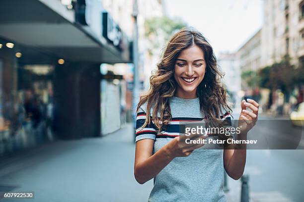 atractiva mujer joven enviando mensajes de texto en la calle - street fotografías e imágenes de stock