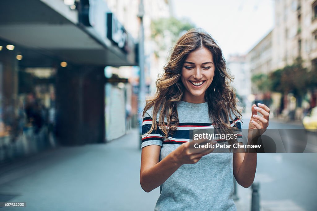 Attractive young woman texting on the street