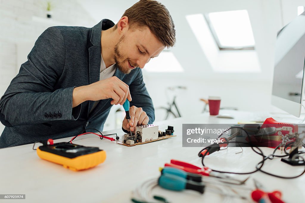 Man Testing Circuit Board In His Office.