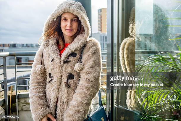 a young woman on a city balcony, in winter. - überzieher stock-fotos und bilder