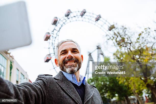 austria, vienna, portrait of smiling businessman taking a selfie at prater - prater park stock pictures, royalty-free photos & images