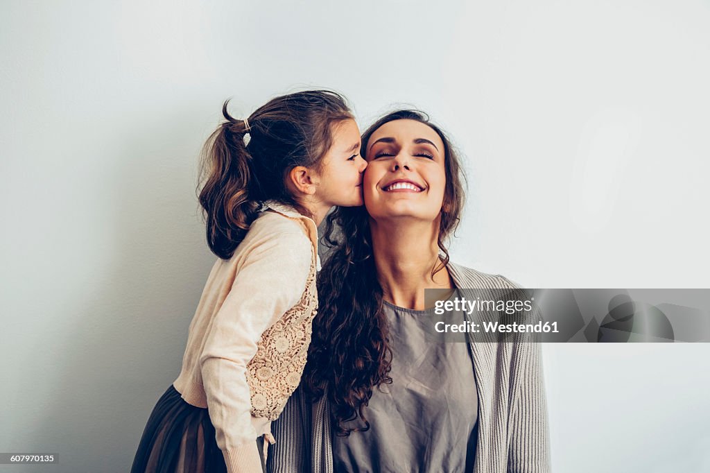 Daughter kissing smiling mother's cheek