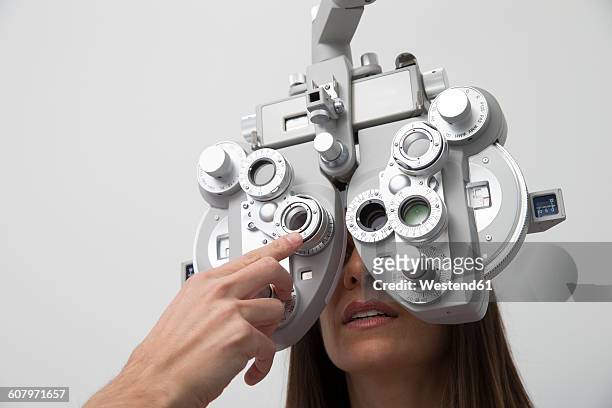 woman at the optometrist making an eye test - eye test equipment imagens e fotografias de stock