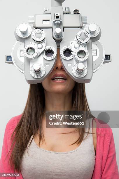 woman at the optometrist making an eye test - phoropter imagens e fotografias de stock