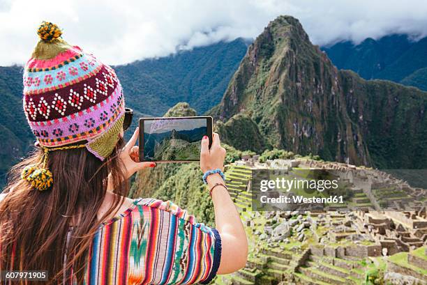 peru, woman taking pictures of machu picchu citadel and huayna picchu mountain with a tablet - berg huayna picchu stock-fotos und bilder