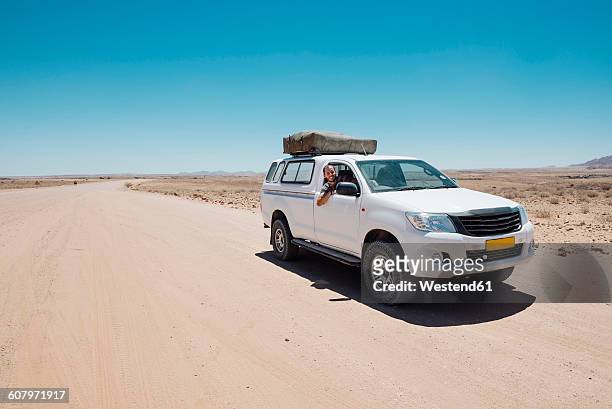 namibia, namib desert, swakopmund, man on a 4x4 car with tent on the roof in a dusty road - repubblica della namibia foto e immagini stock