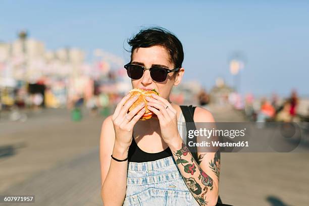 usa, new york, coney island, young woman eating a hamburger - eating burger bildbanksfoton och bilder