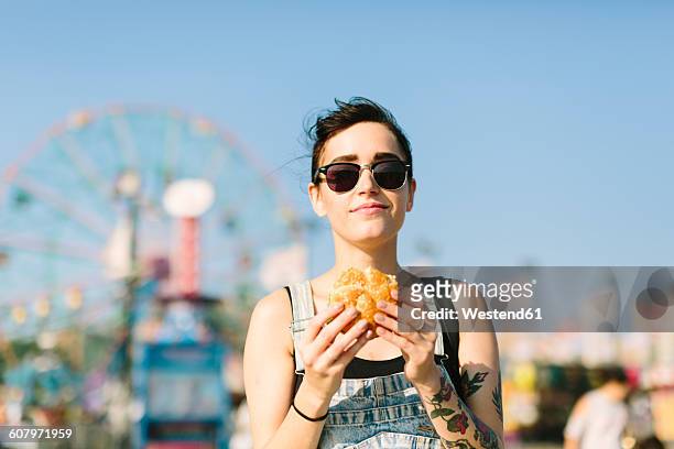 usa, new york, coney island, young woman eating a hamburger - burger portrait stock-fotos und bilder