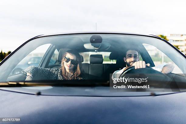 young couple driving in a car - windshield fotografías e imágenes de stock