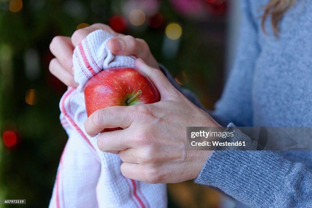 Hand of woman polishing Christmas apple with kitchen towel, close-up