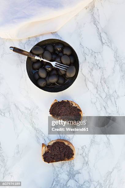 bowl of black olives and two slices of white bread with olive paste on marble - olive noire photos et images de collection
