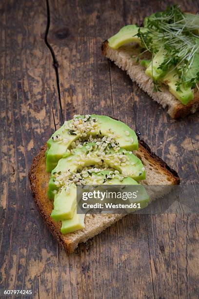 slice of toasted bread with acocado, cress and hemp seeds on wood - hemp seed fotografías e imágenes de stock