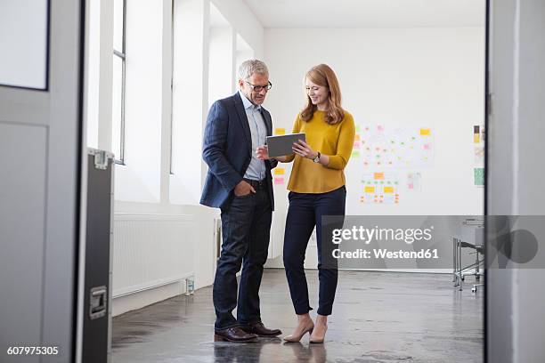 businessman and coworker discussing project in office - man standing talking stock-fotos und bilder