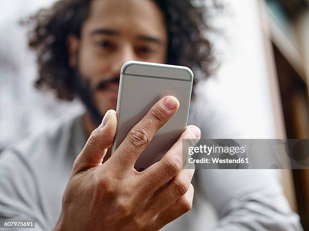 young man holding cell phone - hand smartphone stock-fotos und bilder