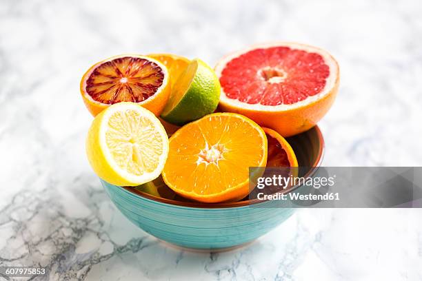 bowl of sliced citrus fruits - bloedsinaasappel stockfoto's en -beelden