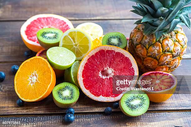 ananas, blueberries, wolfberries, kiwis and sliced citrus fruits on wood - half complete stock pictures, royalty-free photos & images