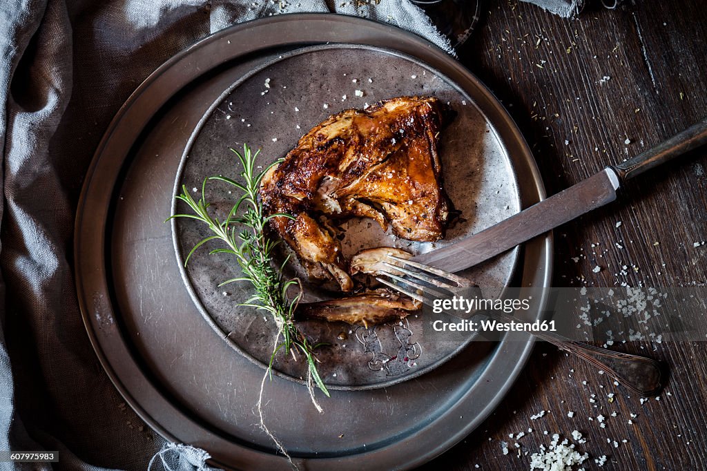 Baked rabbit legs on plate, thyme, rosemary and salt