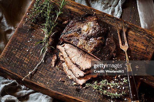 sliced roast beef, rosemary, thyme and sea salt on chopping board - roast beef stock pictures, royalty-free photos & images