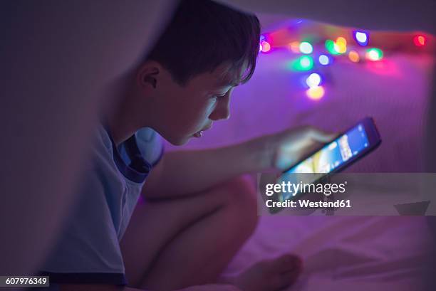 boy sitting under a blanket looking at digital blanket - bright bedroom stock pictures, royalty-free photos & images