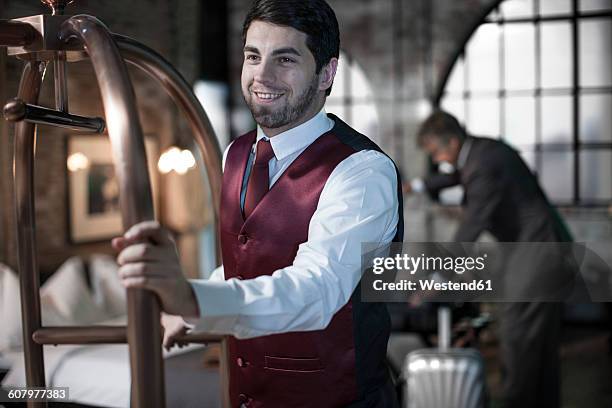 bellboy with trolley, business man with suitcases in background, hotel room - chariot photos et images de collection