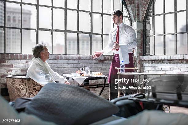 man being served breakfast in hotel room - buttler stock-fotos und bilder