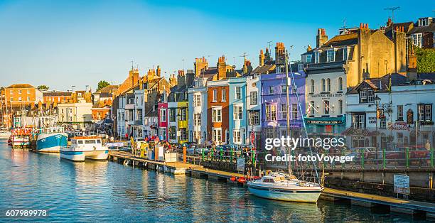 bunte fischerhütten meer hafen resort touristen pubs panorama dorset - englische kultur stock-fotos und bilder