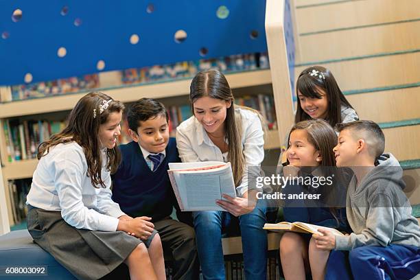 teacher reading books to a group of students - teachers education uniform stockfoto's en -beelden