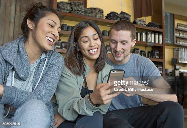 three young persons sitting using a cell phone - philippines friends stock pictures, royalty-free photos & images
