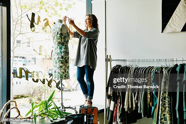 female business owner dressing dress form - retail occupation stockfoto's en -beelden