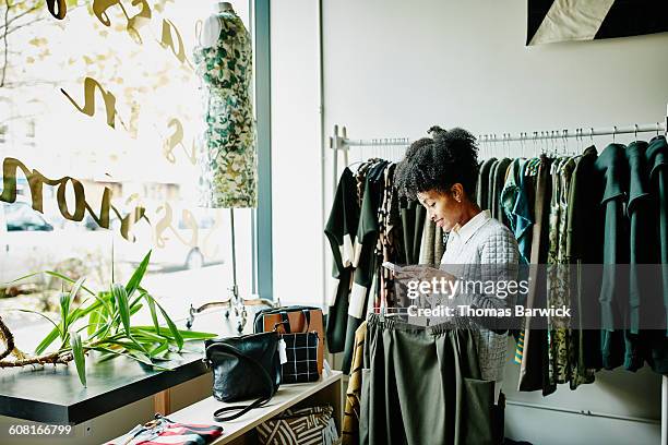 woman checking smartphone while shopping - ブティック ストックフォトと画像