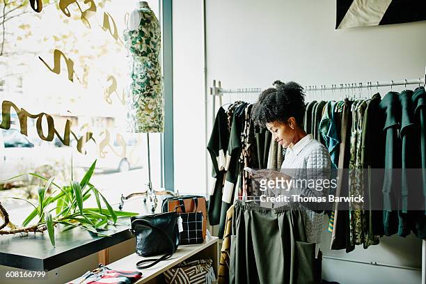 woman checking smartphone while shopping - retail stockfoto's en -beelden