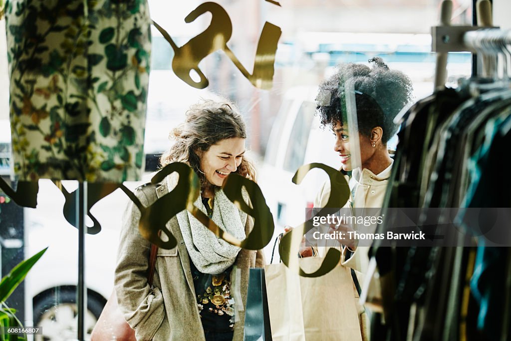 Woman showing friend items in shopping bag