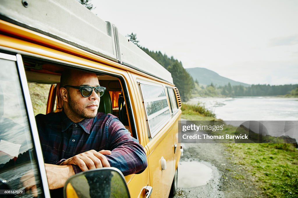 Man in drivers seat of van parked near ocean