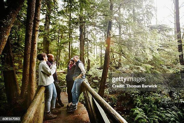 woman taking photo of friends with smartphone - noroeste pacífico de los estados unidos fotografías e imágenes de stock