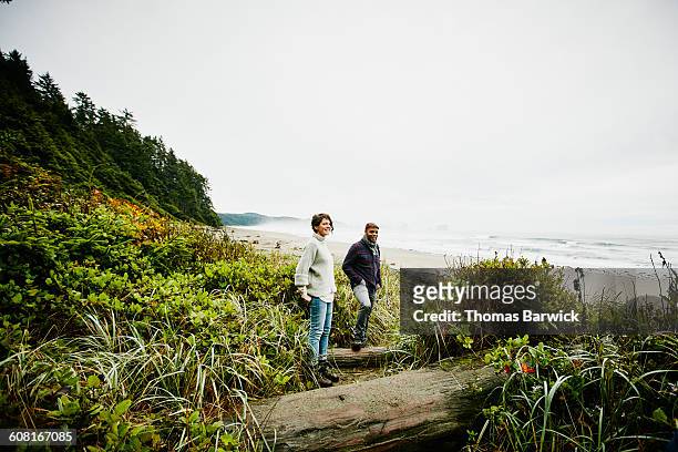 smiling couple standing at beach trailhead - 40 44 jahre paar stehend ganzkörper stock-fotos und bilder