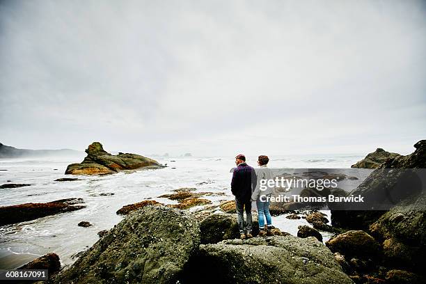 smiling couple standing on boulder looking out - see the bigger picture stock pictures, royalty-free photos & images