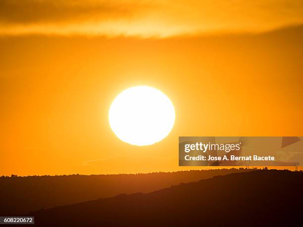 the first plane of a putting sun, hiding between mountains with wind mills - landschaft sommer freigestellt stock-fotos und bilder