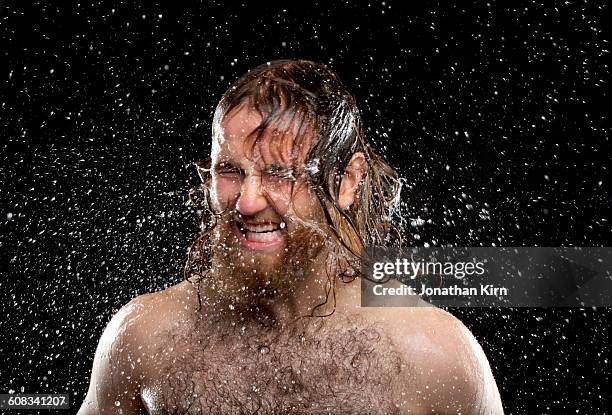 man shakes his head while being doused with water - behaart stock-fotos und bilder