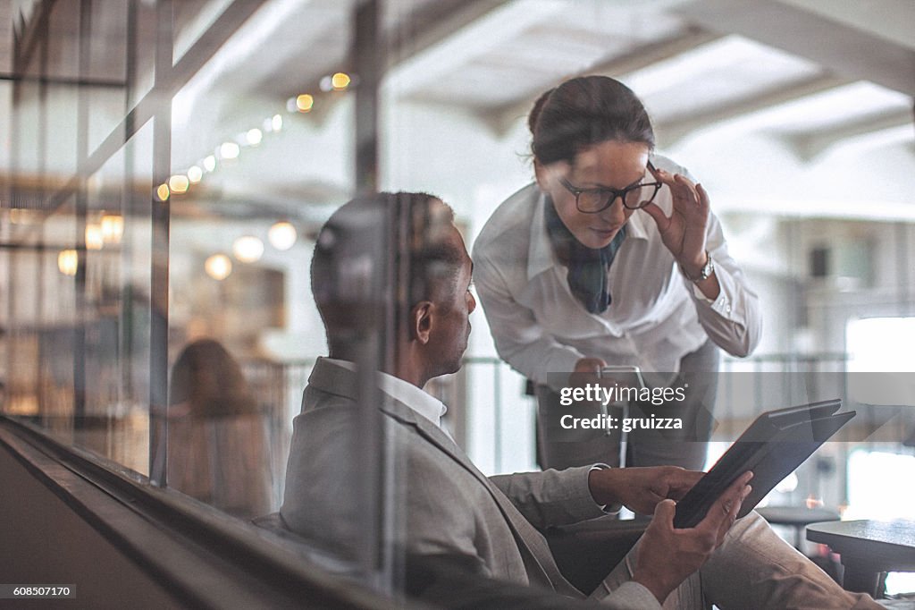 Young businesswoman and man having conversation in modern office space